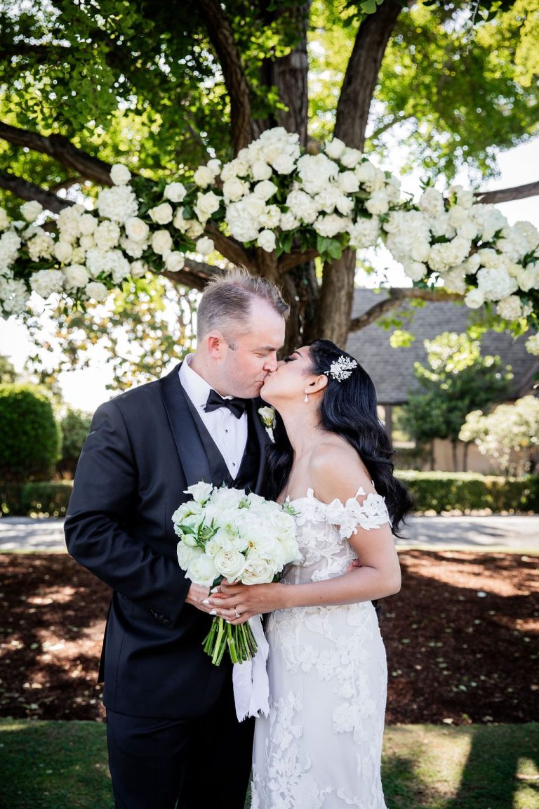 Bride and groom kissing close up holding white bouquet