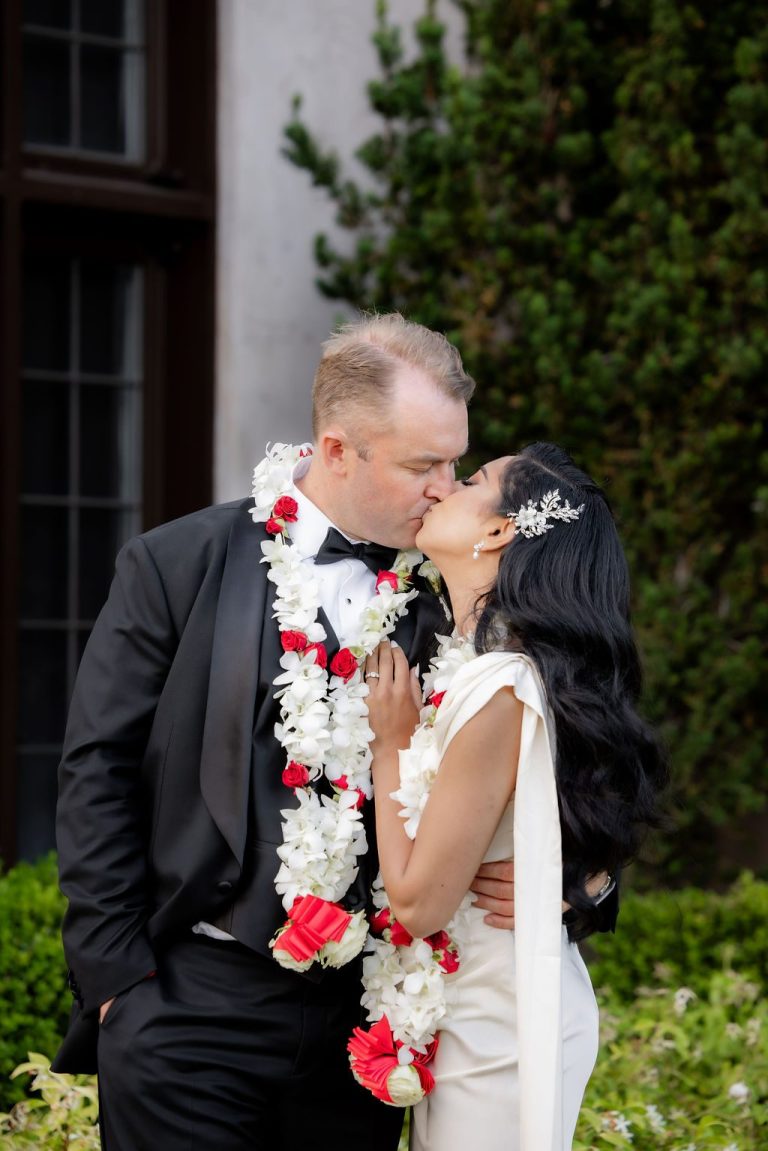 Couple kissing in garden, groom wearing floral garland