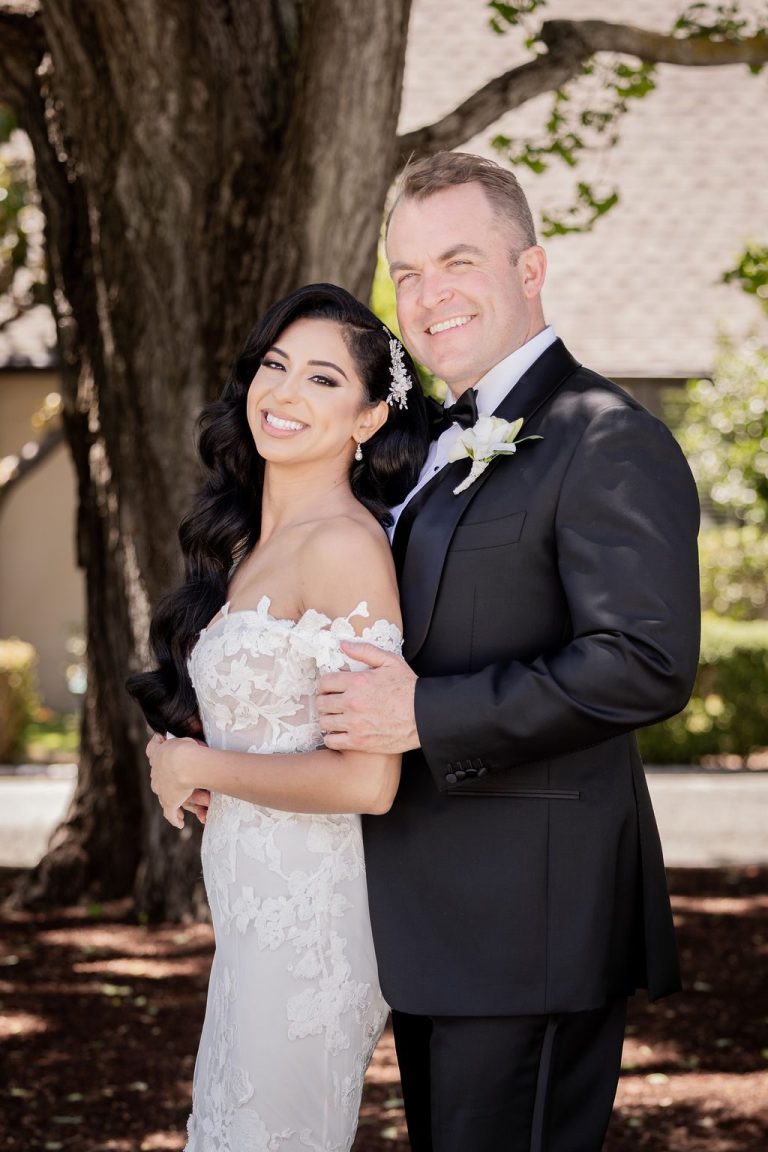 Bride and groom smiling together under leafy trees