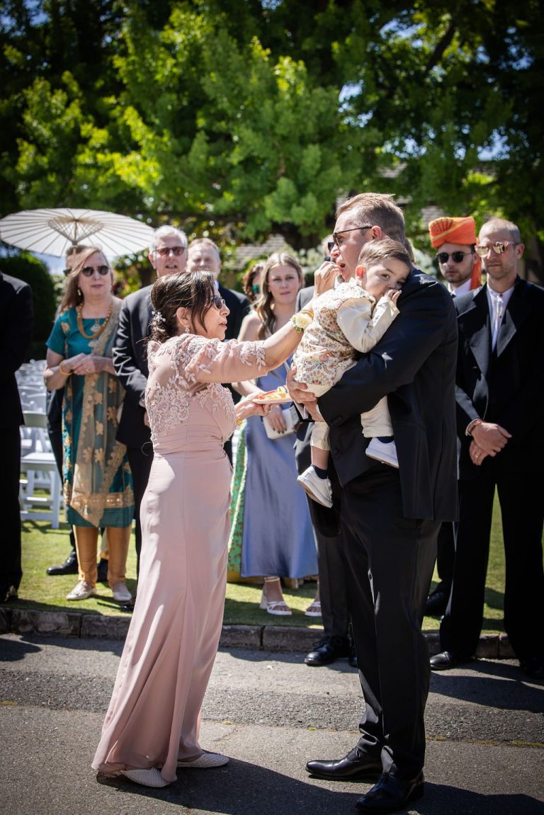 Woman in blush handing child to man during greeting ritual