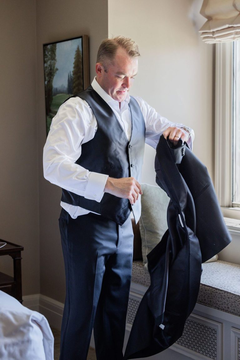 Groom holding jacket preparing to put it on