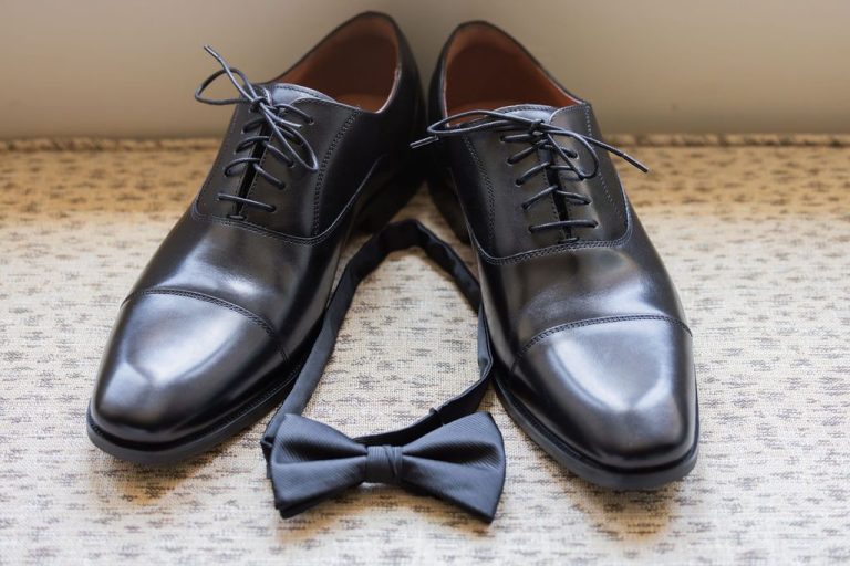 Groom black shoes and bow tie on patterned surface