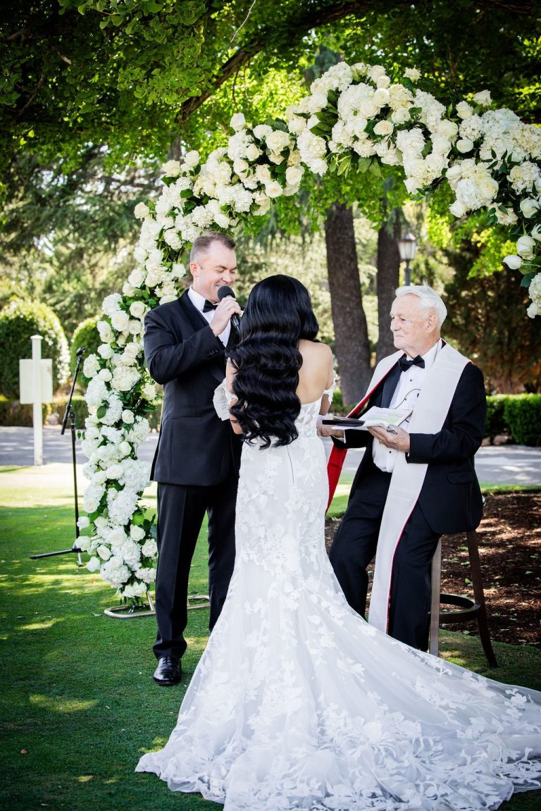 Groom touching face while facing bride at vows