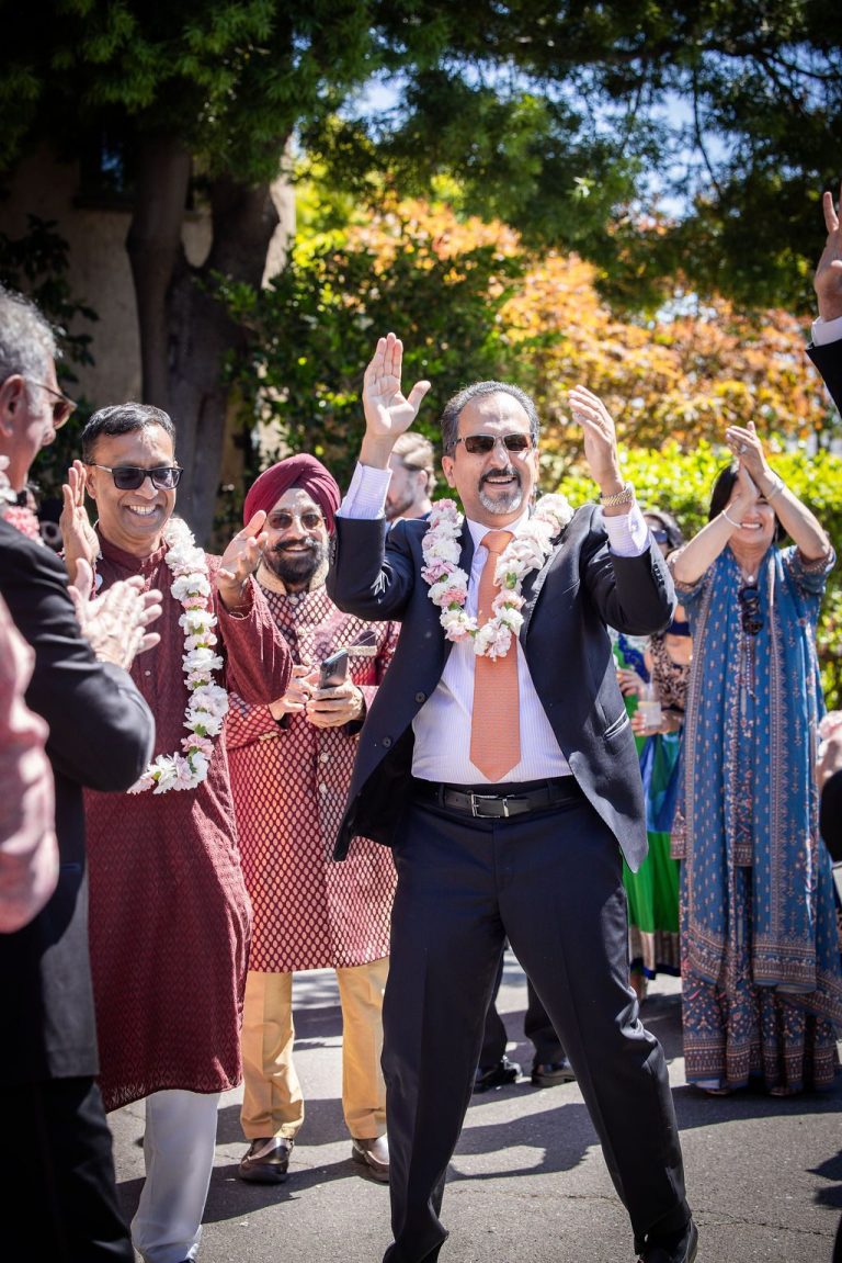 Man with floral garland raising arm joyfully during procession