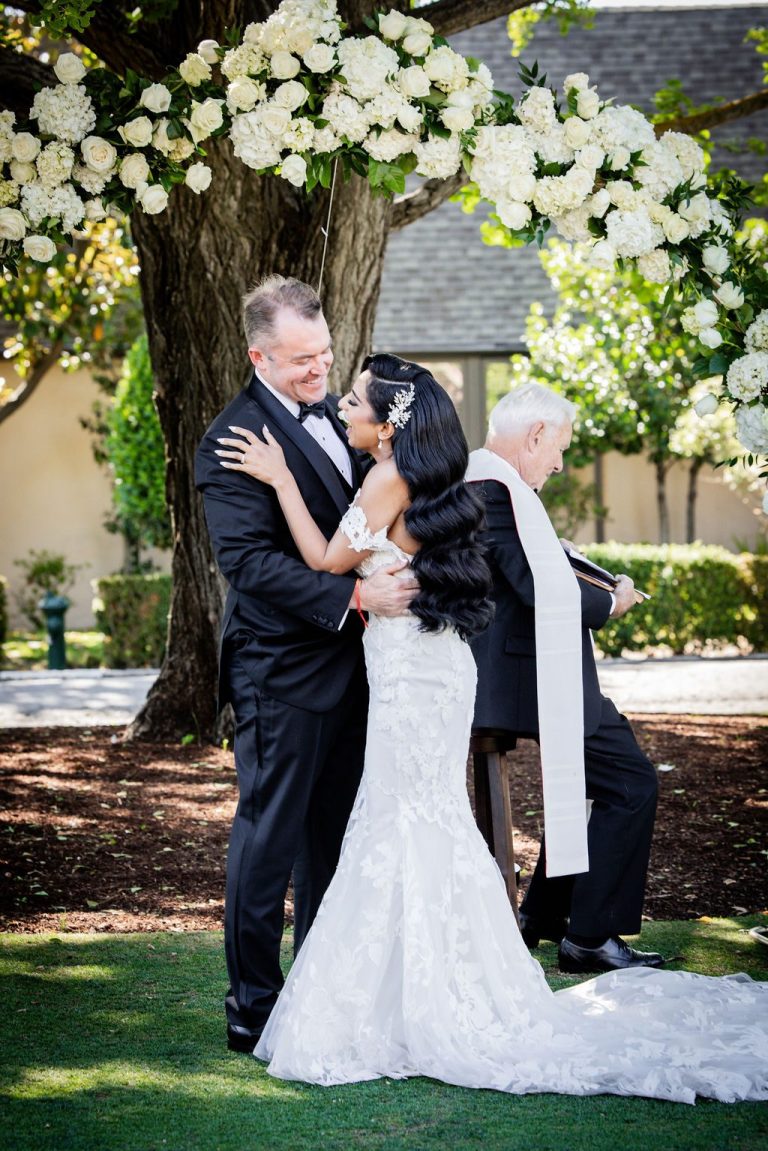 Couple embracing closely under floral arch