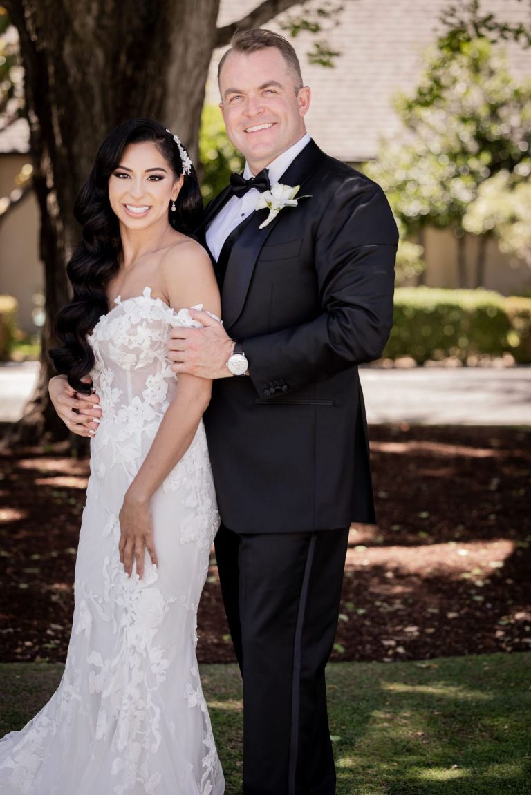 Bride and groom embracing and smiling under trees