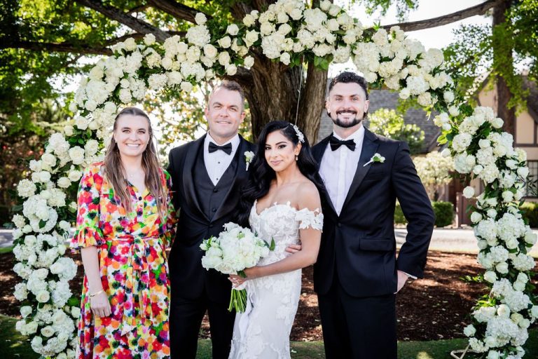 Couple with two friends smiling at floral arch