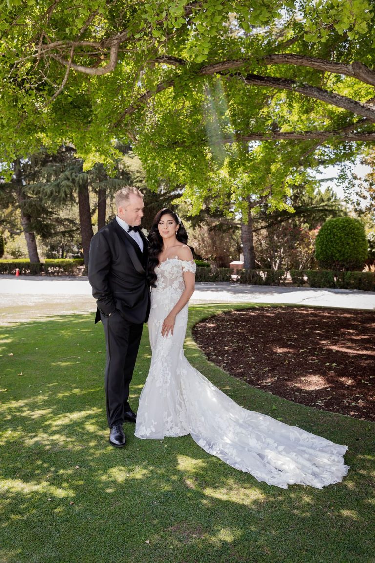 Bride and groom standing together on green lawn