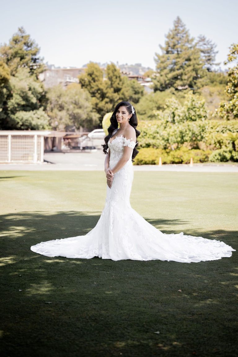Bride standing on lawn with sweeping gown train