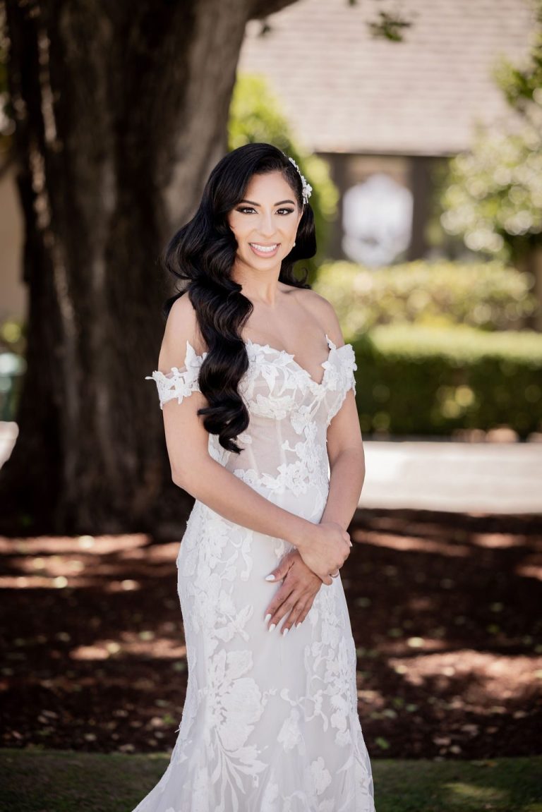 Bride smiling in dappled light in lace gown